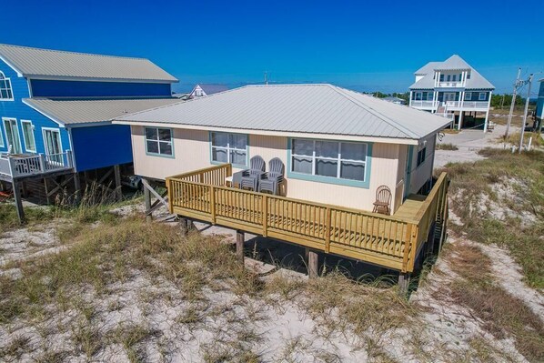 A beachfront house with a wooden deck and a view of the ocean.