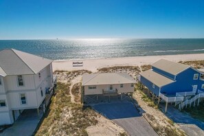A beachfront property with a two-story house, a smaller single-story house, and a blue building with a balcony.
