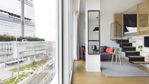 Un intérieur moderne avec une grande fenêtre, un escalier et un coin salon.