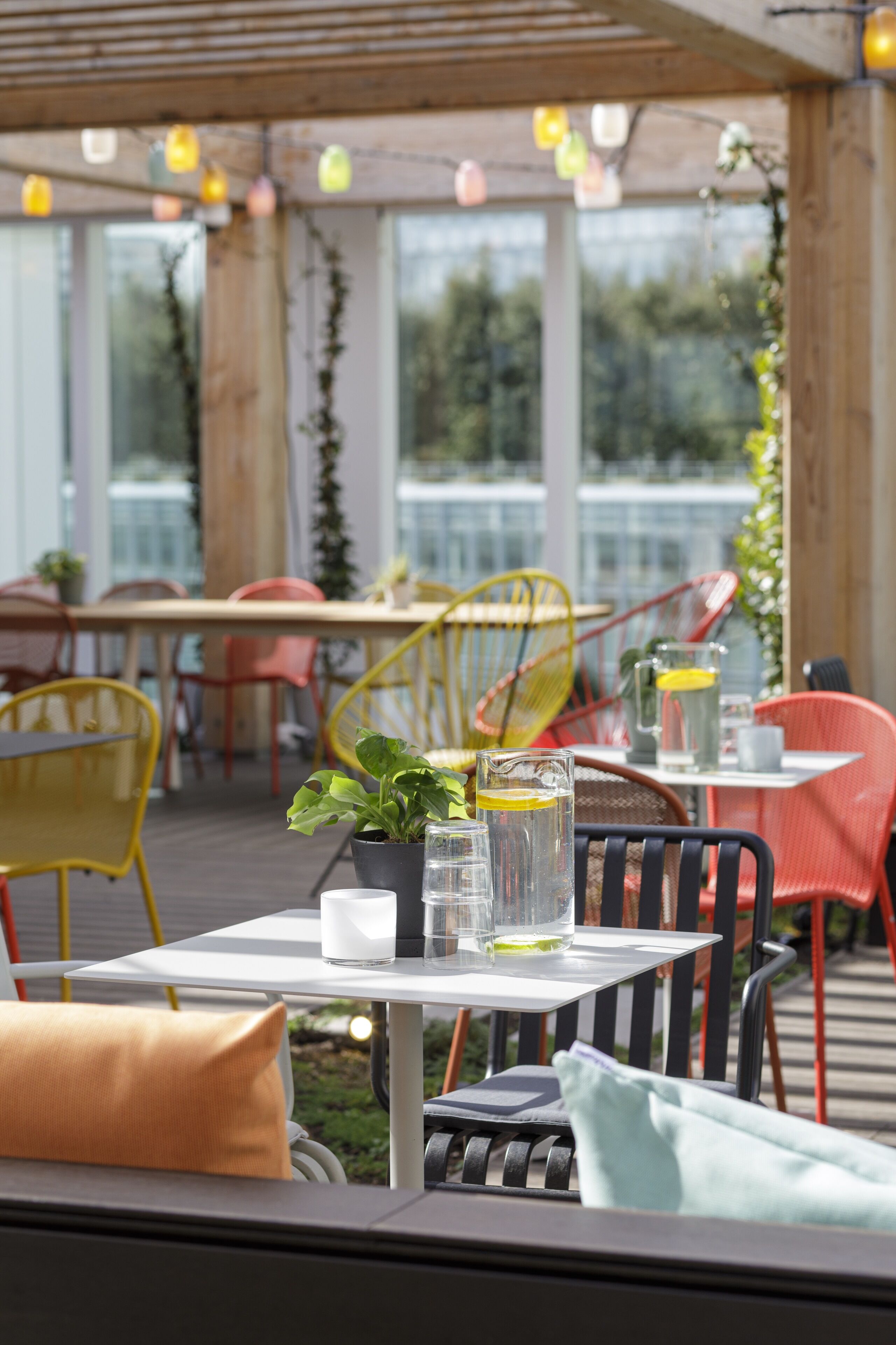 An outdoor dining area with tables and chairs, potted plants, and hanging lights.