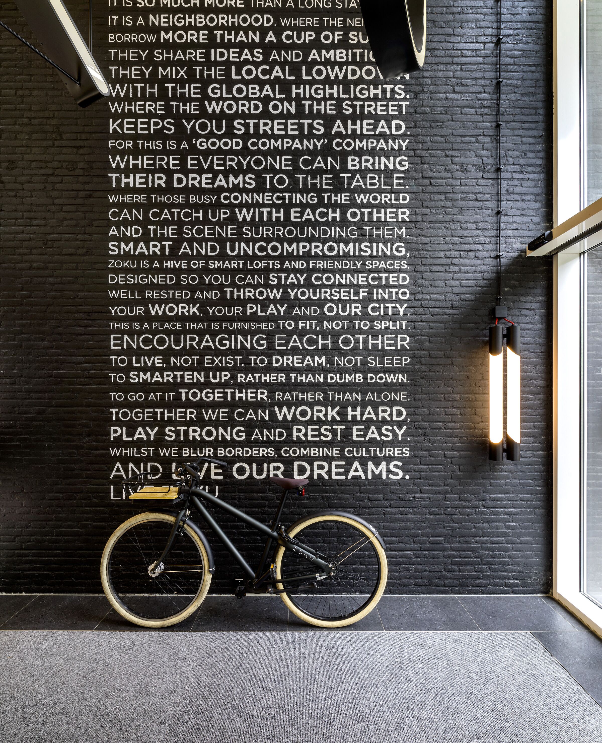 A black brick wall with motivational text and a bicycle leaning against it.
