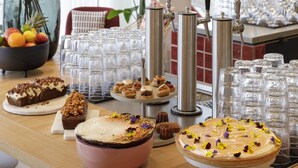 Une table de buffet garnie de divers plats, un grand vase rempli de fleurs et un bar avec des robinets.