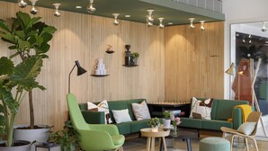 Un salon moderne avec un canapé vert, un fauteuil vert, une table basse et une grande plante en pot.
