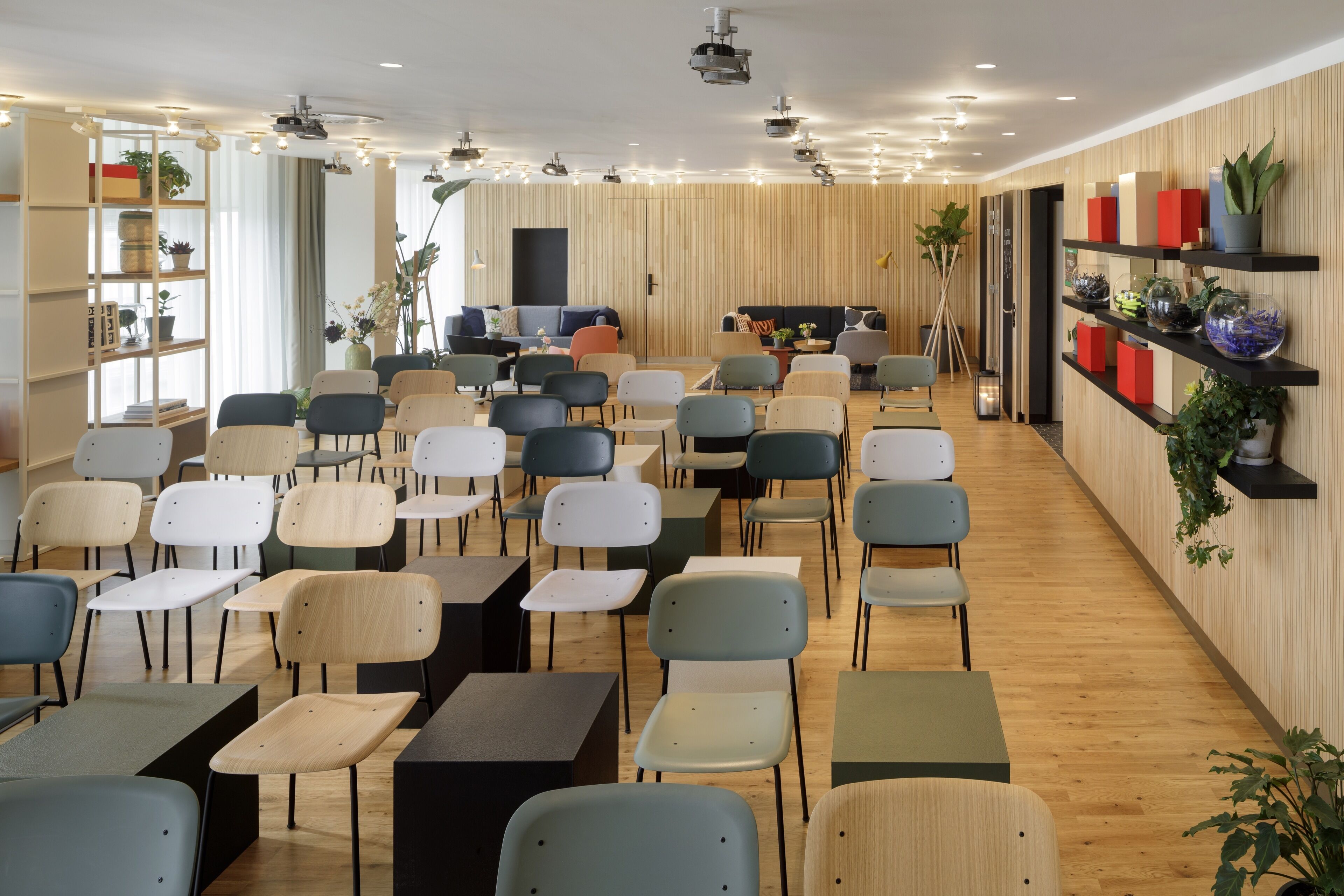 A modern indoor space with multiple seating areas, including tables and chairs, and shelves with decorative items.