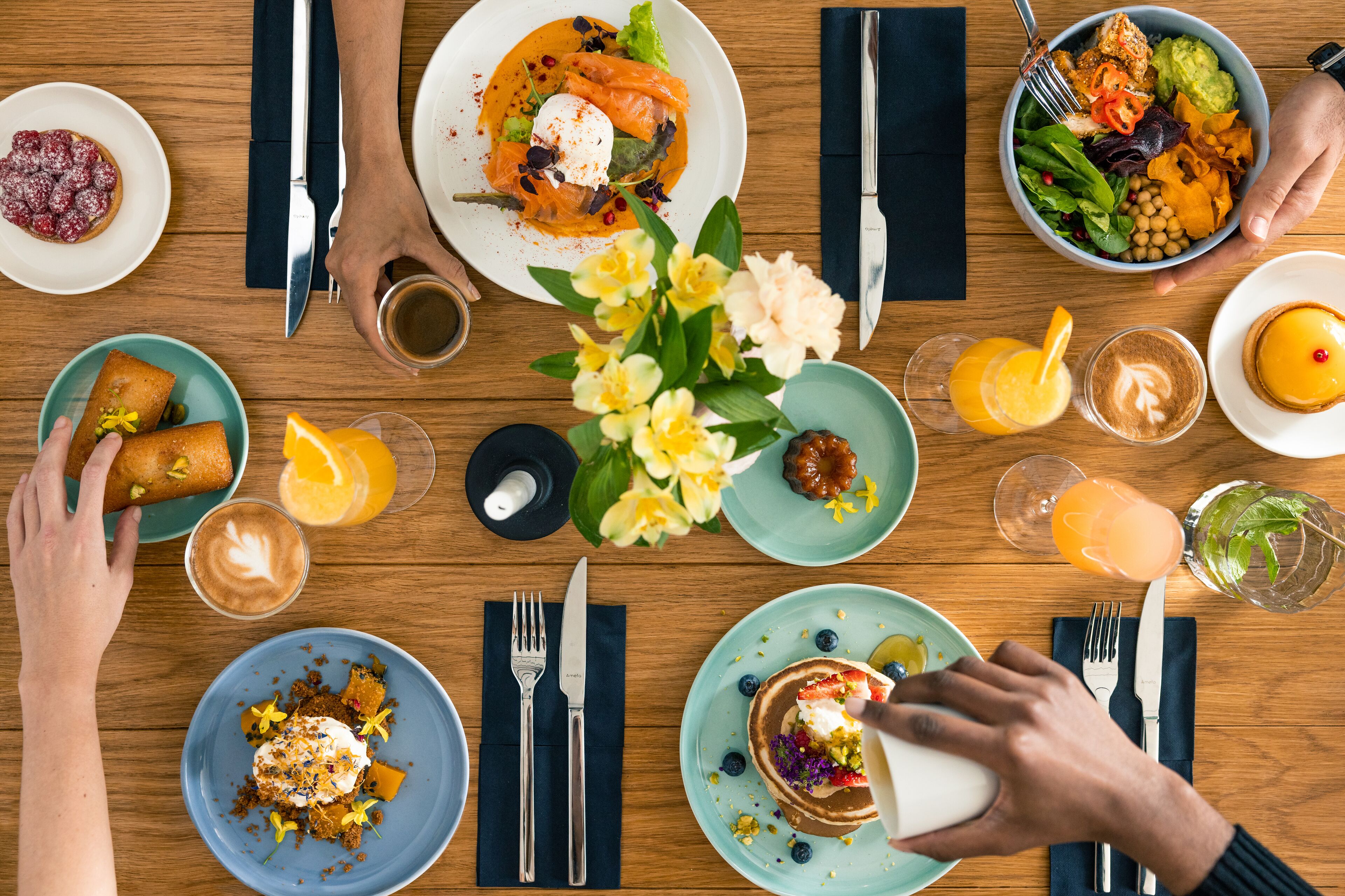 A dining table with various dishes, including pancakes, a salad, and a dessert.