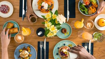 A dining table with various dishes, including pancakes, a salad, and a dessert.