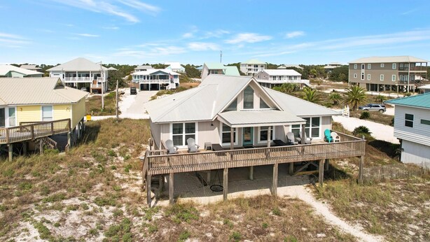 Ein Küstenhaus mit Holzterrasse, großen Fenstern und Blick auf den Strand.