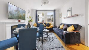 Ein modernes Wohnzimmer mit einer Couch, Sesseln, einem Couchtisch und einem Fernseher.