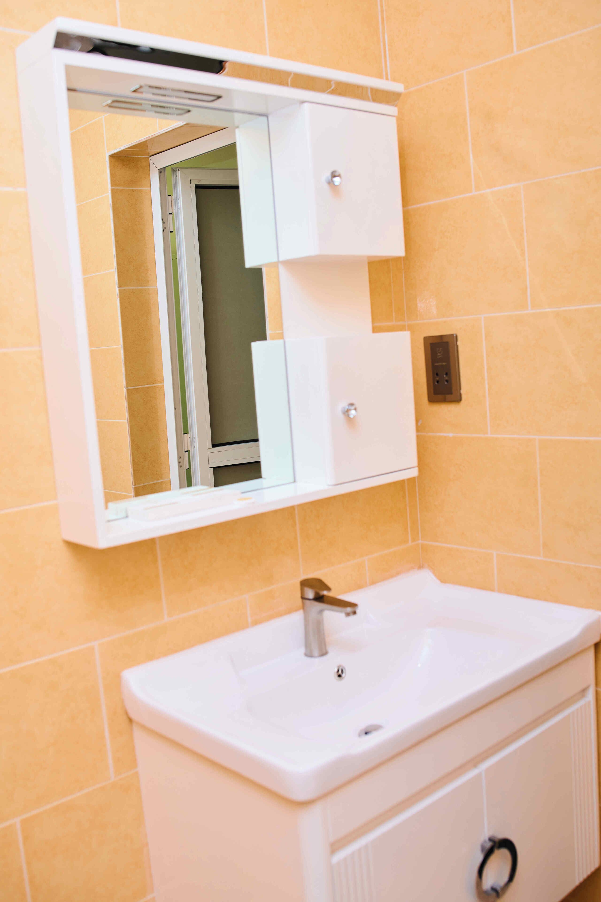 Ein Badezimmer mit einem weißen Waschbecken, einem Spiegel und einem Schrank.