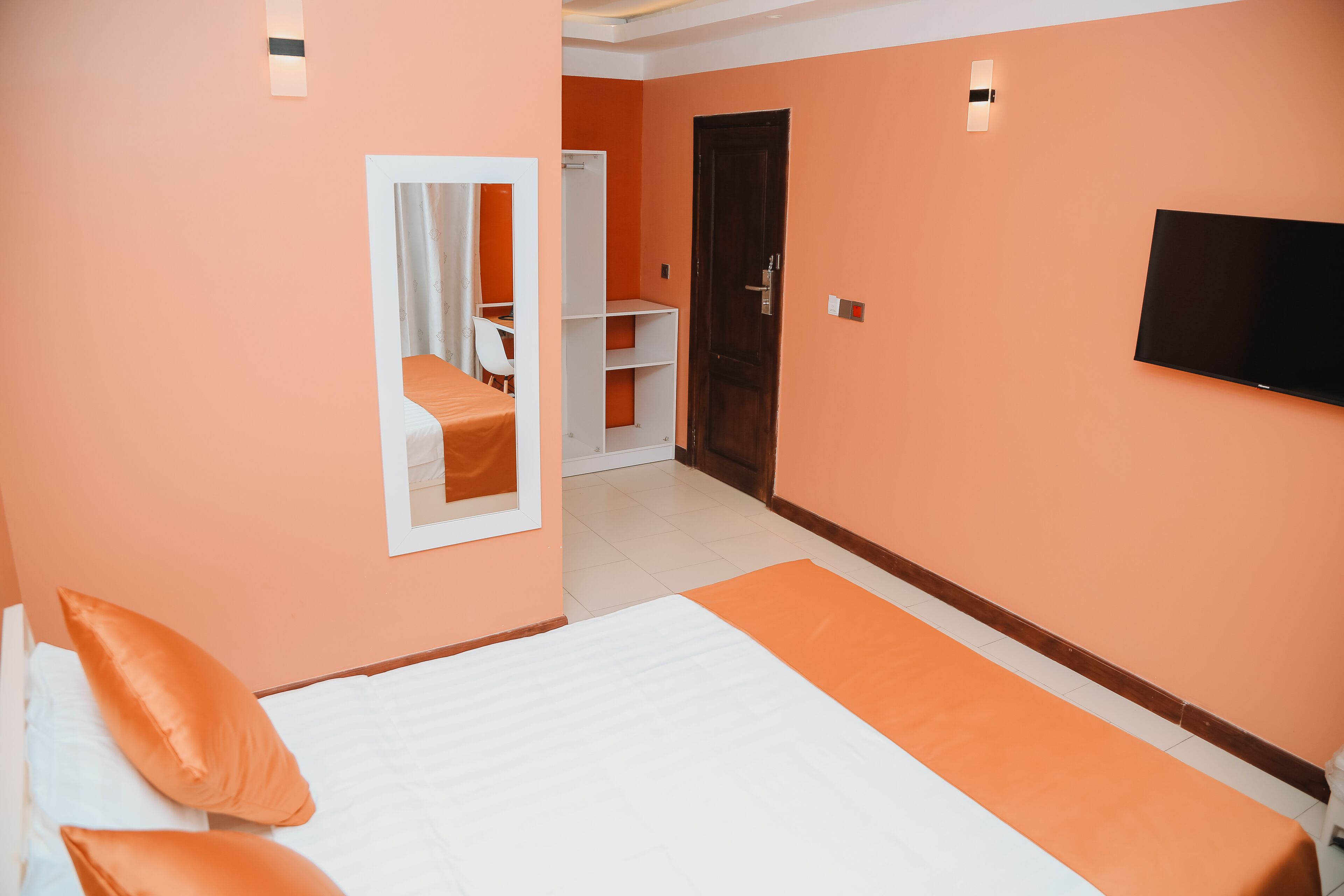 A hotel room with a bed, a TV, a wardrobe, and a mirror.