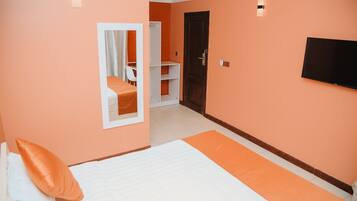 A hotel room with a bed, a TV, a wardrobe, and a mirror.