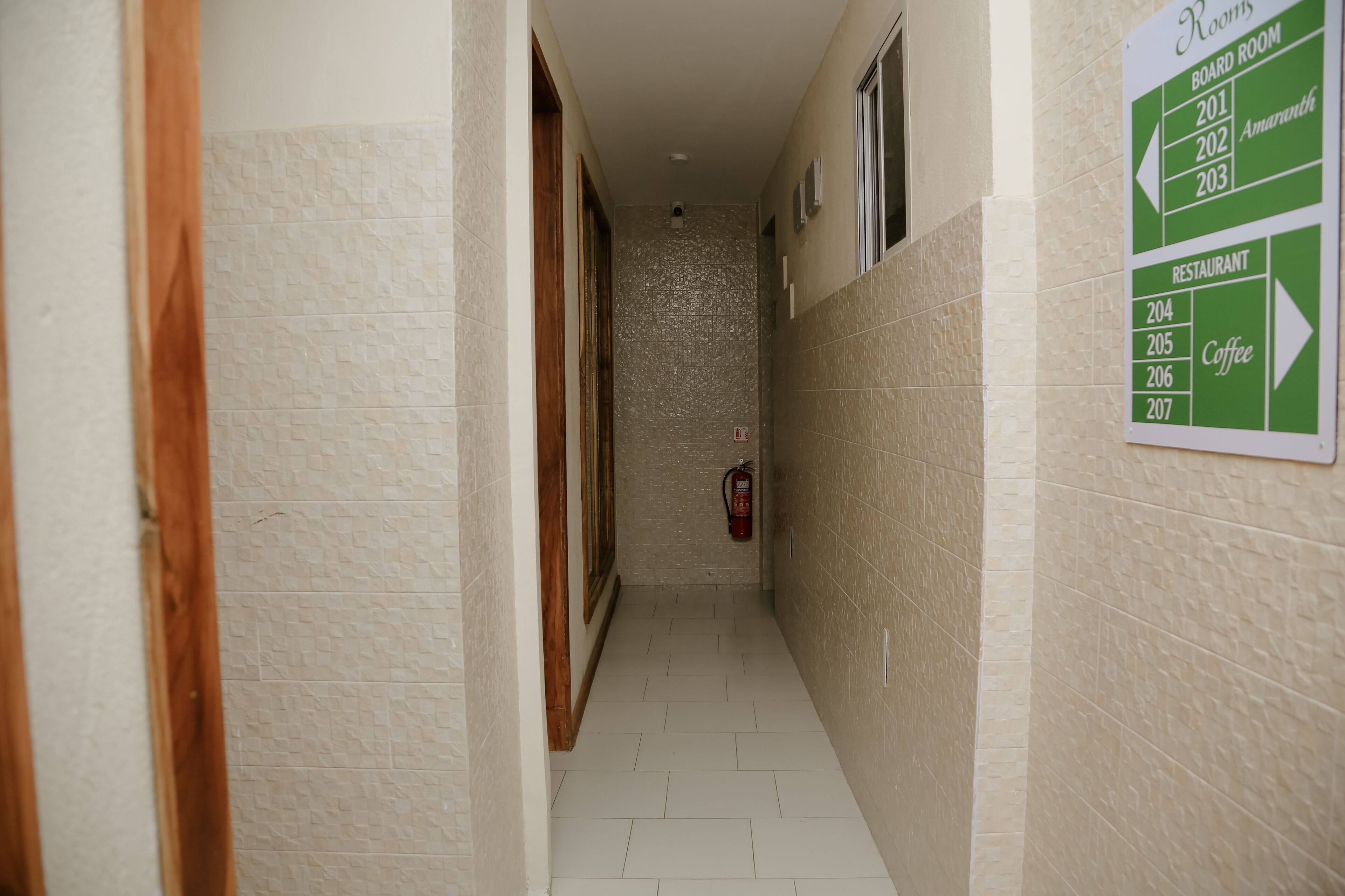 A narrow hallway with a sign indicating room numbers and a coffee area.
