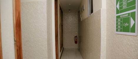A narrow hallway with a sign indicating room numbers and a coffee area.