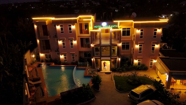 A multi-story hotel with a swimming pool, well-lit exterior, and a sign reading "HOTEL AMARANTH". - Hotel Amaranth (Dar es Salaam)