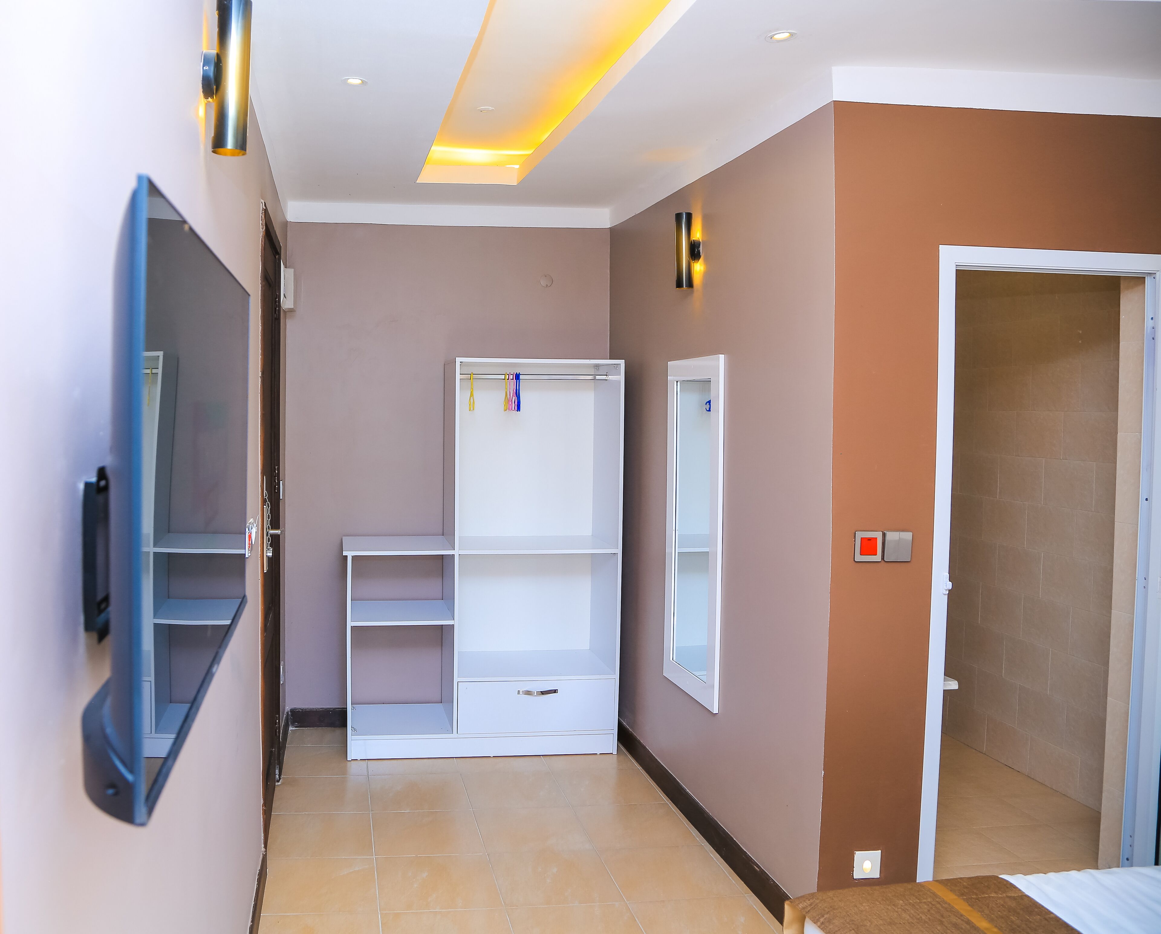 A hallway with a white wardrobe, a small table, and a door leading to another room.