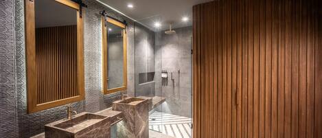 Un baño moderno con un espejo grande, dos lavamanos y una zona de ducha.