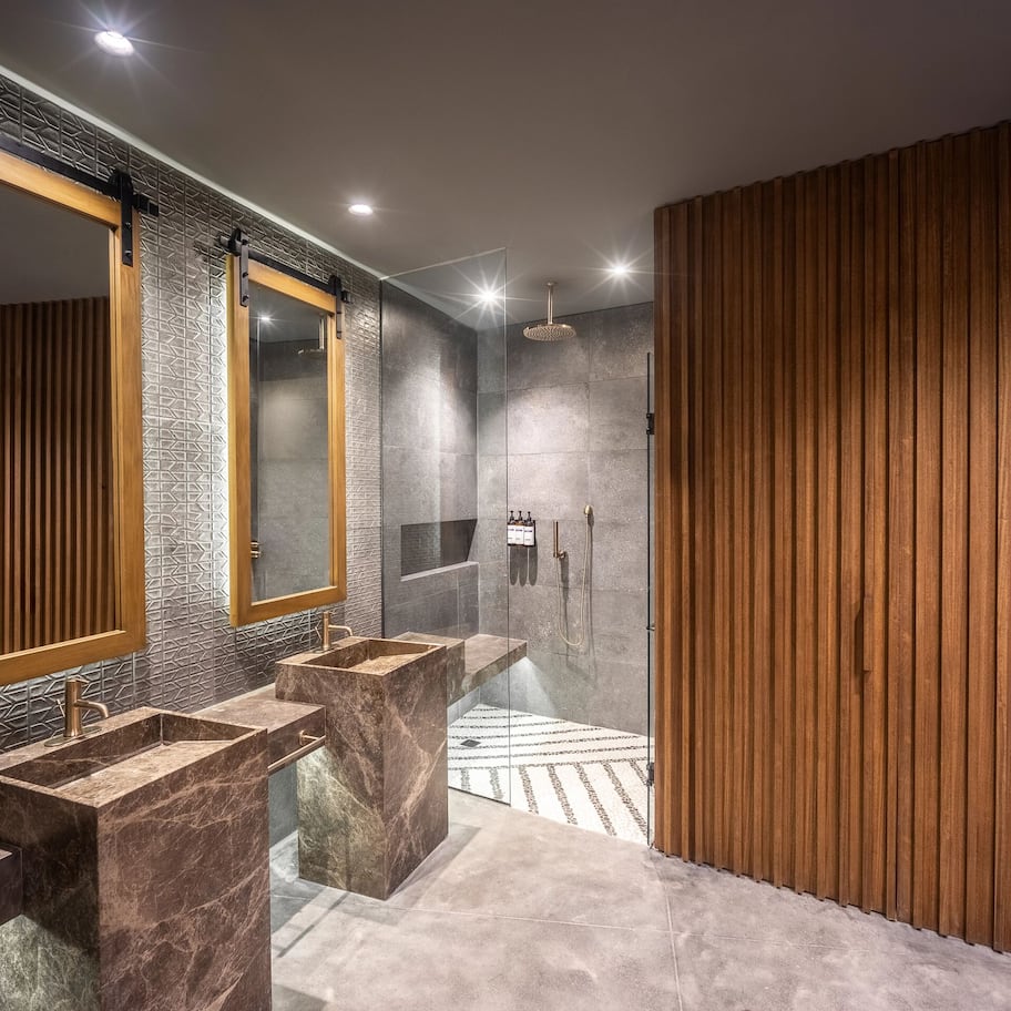 A modern bathroom with a large mirror, two sinks, and a shower area.