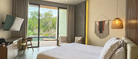Un dormitorio moderno con una cama grande, un escritorio, una silla, un televisor en la pared y un balcón con vistas a zonas verdes.
