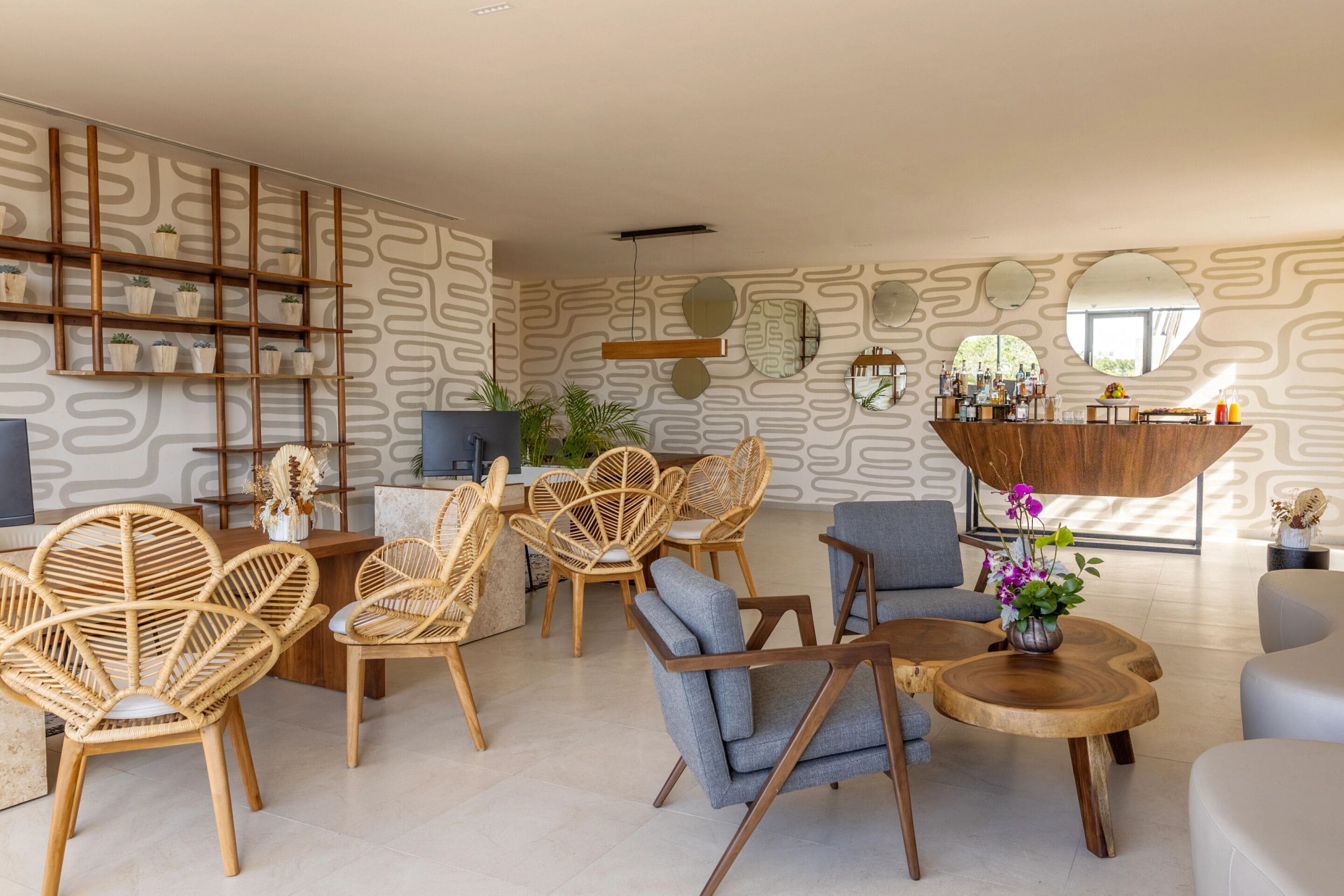 A modern living room with wicker chairs, a round wooden coffee table, and a bar area with a mirror and plants.