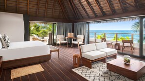 A spacious room with a bed, sofa, and a dining area. The room has a wooden floor and a thatched roof. - Secrets Tulum Resort & Beach Club - Adults Only - All Inclusive (Tulum)
