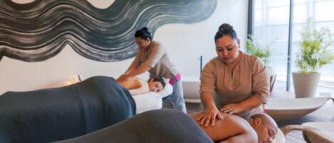 A massage therapy room with two clients receiving treatment.