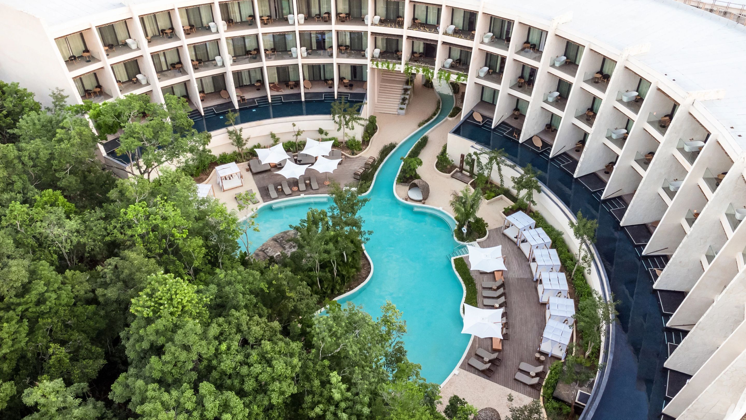 A hotel with a central swimming pool, multiple balconies, and outdoor seating areas.