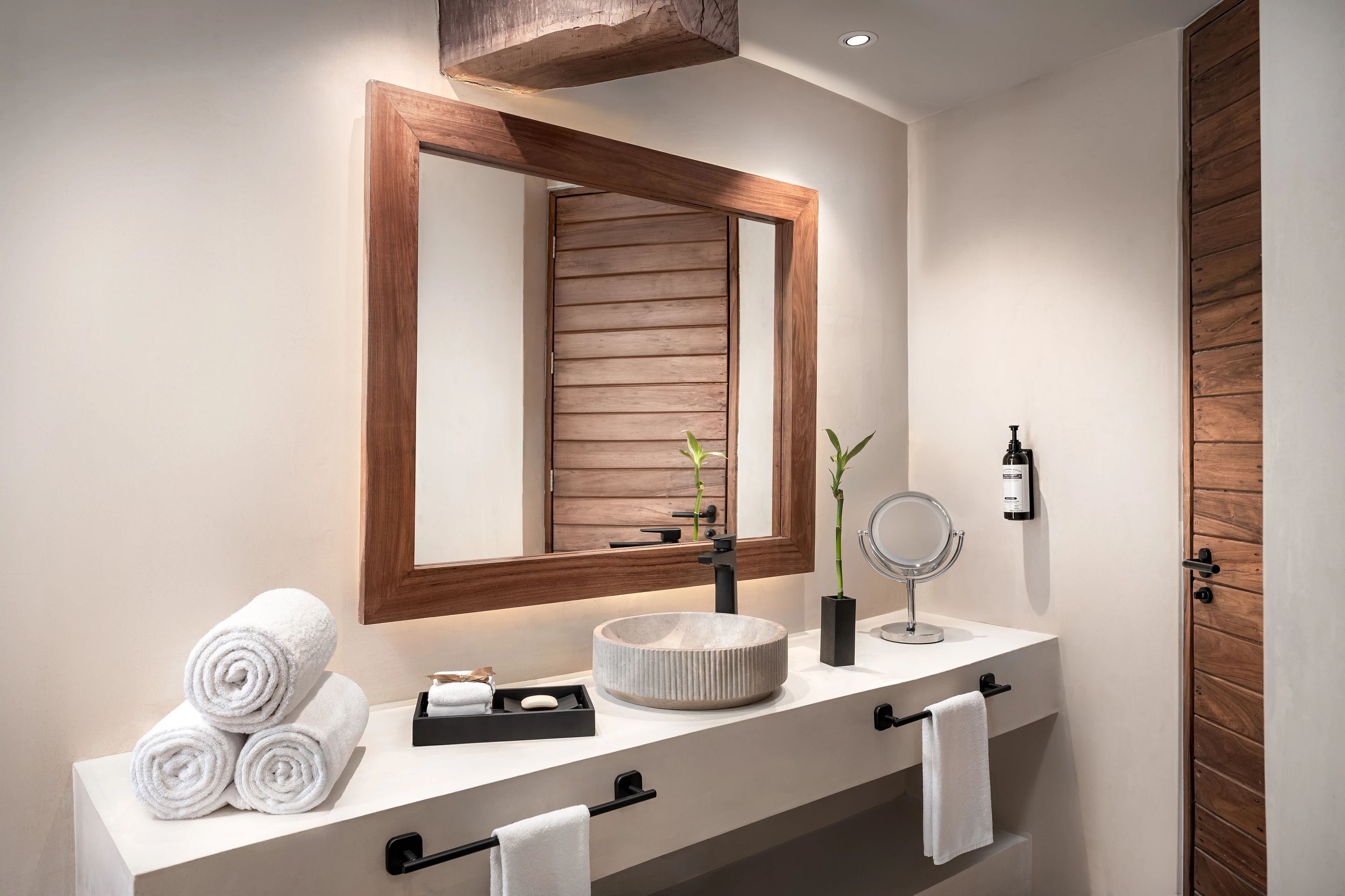 Une salle de bain moderne avec un miroir encadré en bois, un lavabo rond posé sur un meuble et des serviettes soigneusement pliées sur le comptoir.