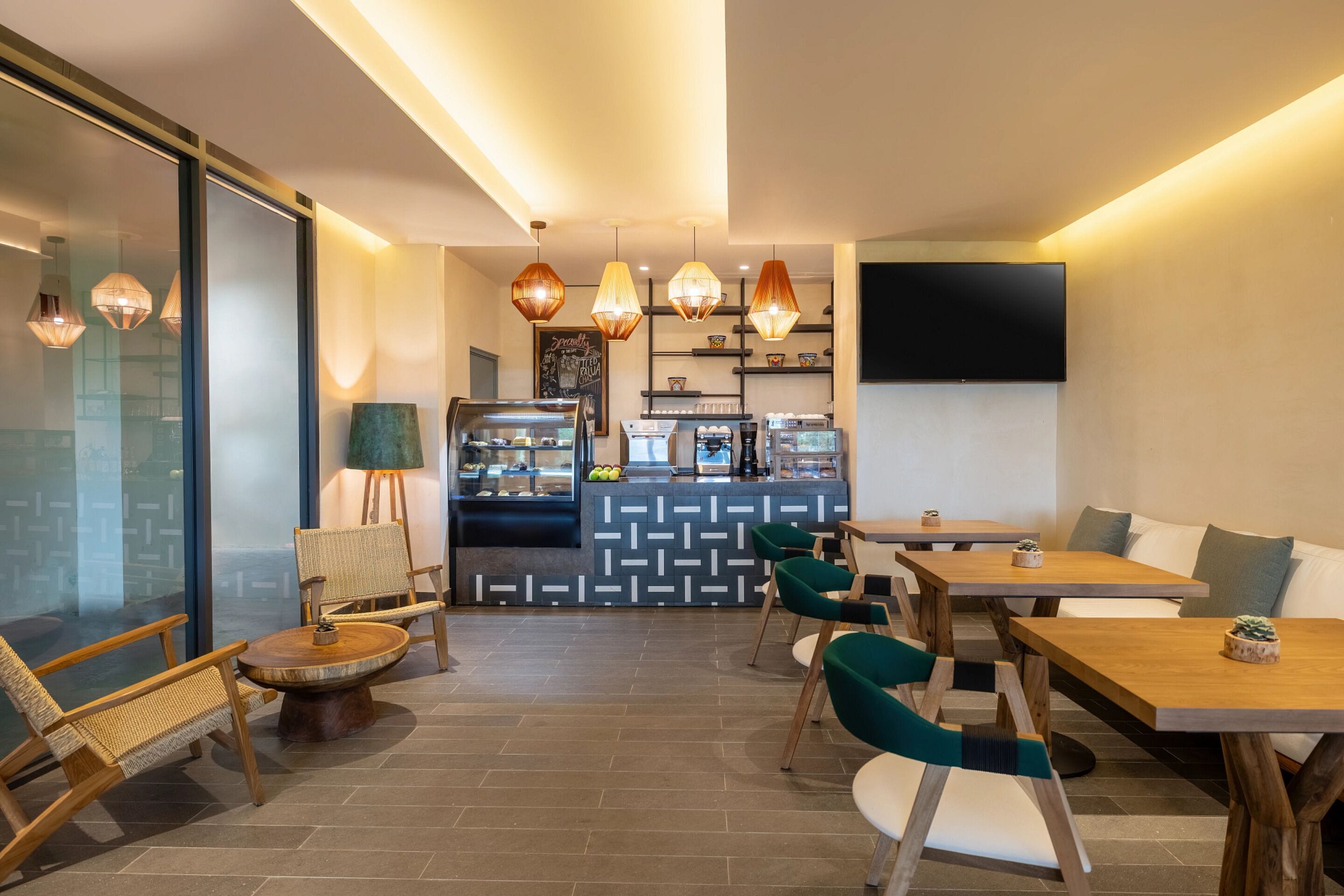 Een modern café met houten meubels, hanglampen en een toonbank met koffiemachines.