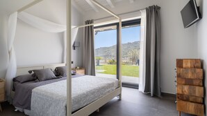 A bedroom with a four-poster bed, a wooden dresser, and a TV mounted on the wall. - 3 Bedroom Modern Villa, Pool, Savoca, East Sicily (Savoca)