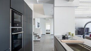 A modern kitchen with built-in appliances, a central island, and a view into the living area. - 3 Bedroom Modern Villa, Pool, Savoca, East Sicily (Savoca)