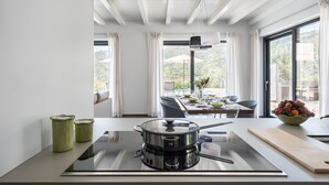 A modern kitchen with a large stove, dining table, and a view of the outdoors. - 3 Bedroom Modern Villa, Pool, Savoca, East Sicily (Savoca)