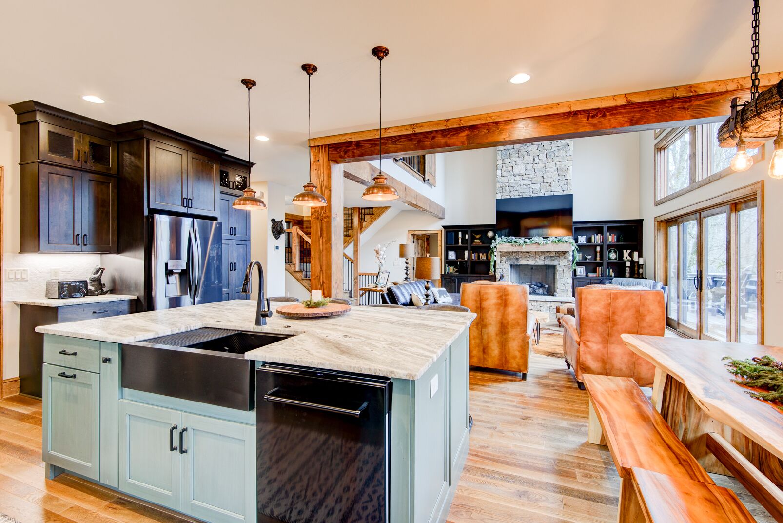A spacious kitchen with a central island, wooden beams, and pendant lighting.