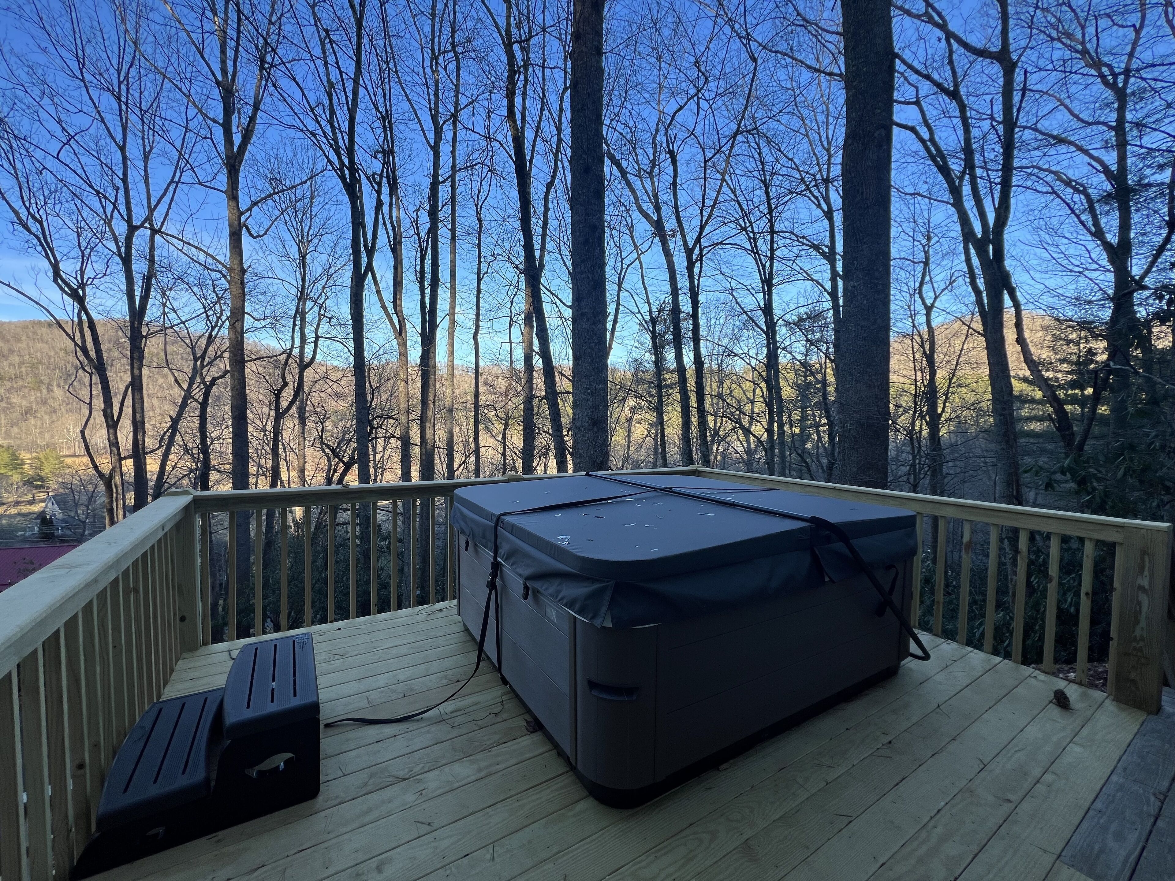 Una terraza con zona de estar techada y vista a un paisaje boscoso.