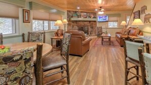 A cozy living room with wooden floors, leather sofas, and a fireplace.