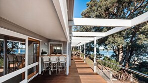A covered outdoor deck with a wooden floor, white chairs, and a table. - Bancroft Haven: Nestled above the marina boasting views across Bancroft Bay (Metung)