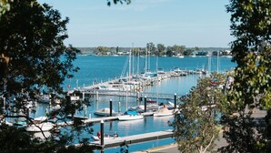 A marina with boats docked, a clear sky, and trees framing the view. - Bancroft Haven: Nestled above the marina boasting views across Bancroft Bay (Metung)