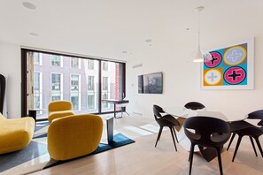 Ein modernes Interieur mit Essbereich, gelben Stühlen und einem großen Fenster mit Blick auf Gebäude.