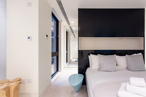 Ein modernes Hotelzimmer mit einem großen Bett, einem Nachttisch und Blick auf den Flur.
