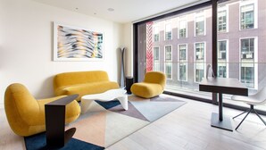 Ein modernes Wohnzimmer mit einem gelben Sofa, einem weißen Couchtisch und einem Esstisch mit Stühlen.