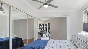 A bedroom with two beds, a ceiling fan, and a large mirror. - Karinyah - Panoramic Waterfront Views (Summerland Point)