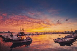 Een jachthaven in de zonsondergang, met diverse boten afgemeerd, kalm water en een heldere lucht.