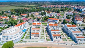 A modern residential area with a central building featuring a curved facade, surrounded by smaller houses with red roofs.
