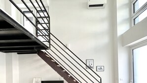 Ein modernes Wohnzimmer mit Treppe, Flachbildfernseher und einer Couch.