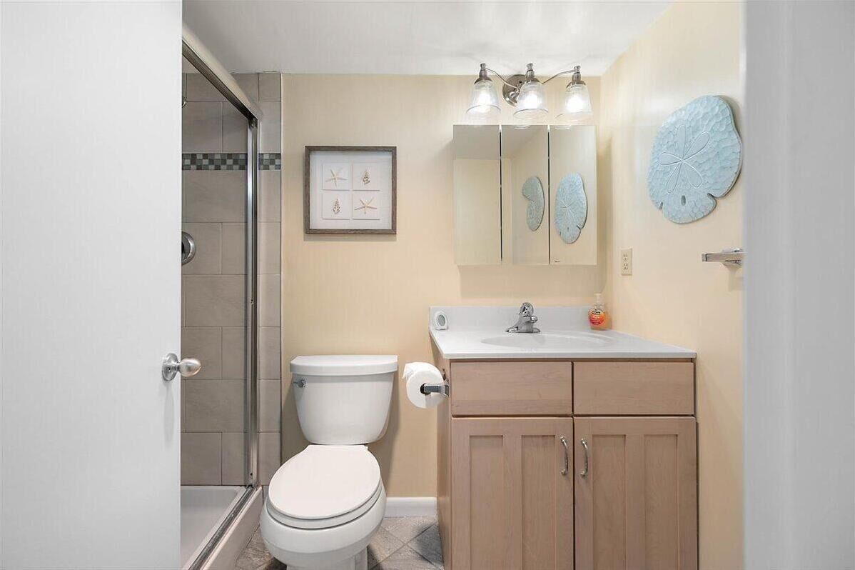 A bathroom with a toilet, shower, sink, and cabinet.
