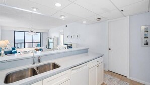 Una cocina moderna con armarios blancos, un lavamanos de acero inoxidable y un lavavajillas empotrado.