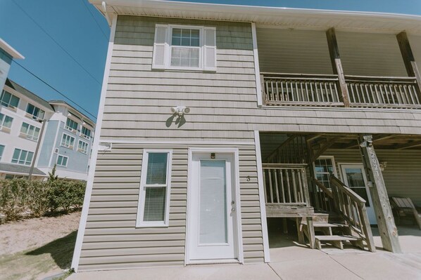 A two-story building with a balcony on the upper floor, a front door, and a small porch area.