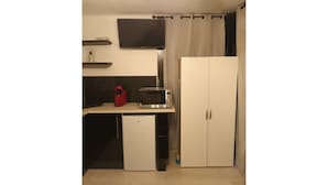 A compact kitchen with a microwave, a small refrigerator, and a cabinet.