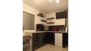 A compact kitchen with black cabinets, a white countertop, and a small sink.