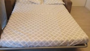 A small, single-bed room with a patterned bedspread and pillows.
