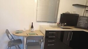 A small kitchen with a round table, two chairs, a bottle, and a black cabinet.
